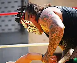 Close up of a Mexican wrestler wearing white facepaint with black and red lines on it.
